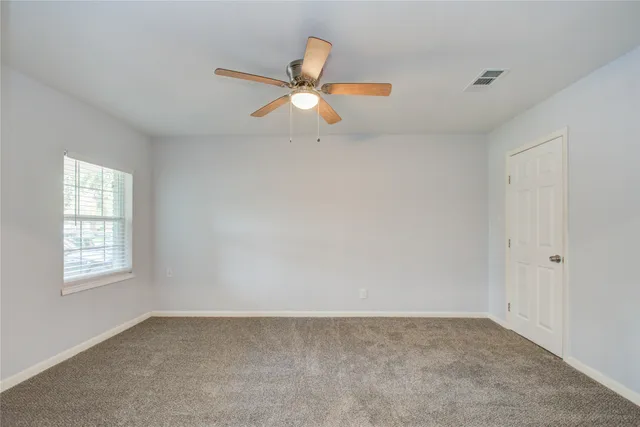 an empty room with windows and fan