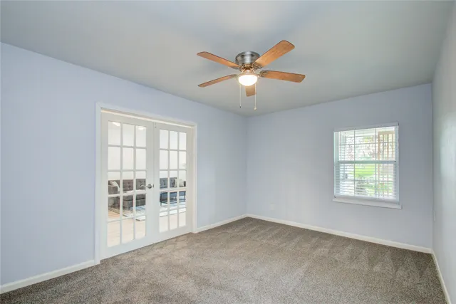an empty room with windows and fan