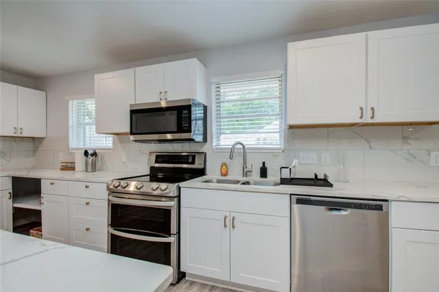 a kitchen with white cabinets appliances and a window