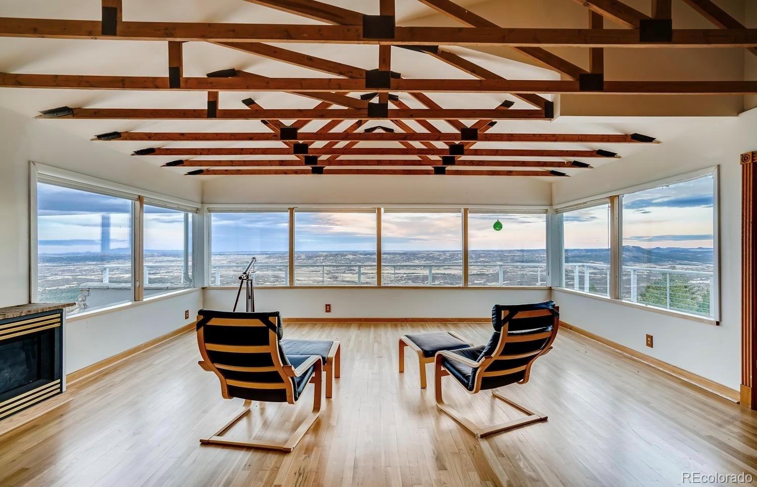 1150 North Madge Gulch Road Sedalia, CO 80135 - Photo 19 of 49 a living room with furniture a floor to ceiling window and wooden floor