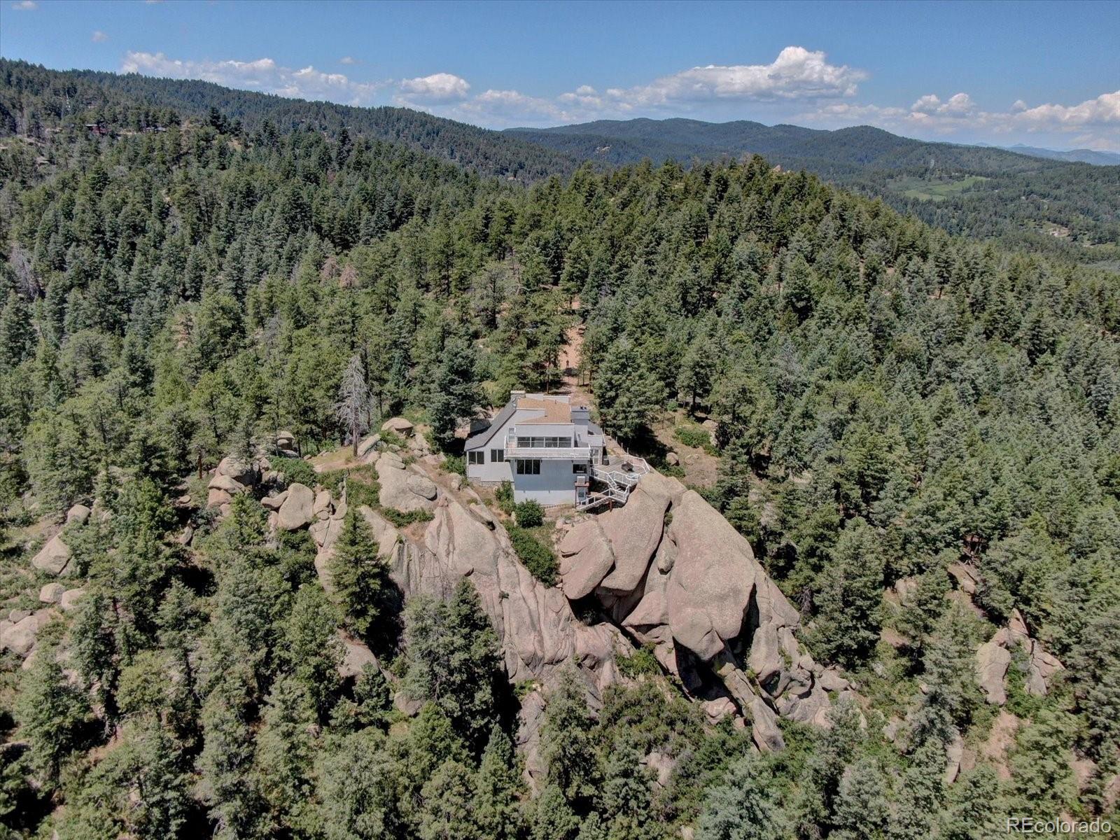 1150 North Madge Gulch Road Sedalia, CO 80135 - Photo 45 of 49 a view of a lush green hillside and a houses