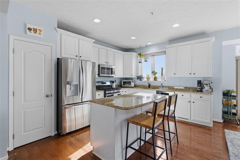 44 Coolidge Drive McKees Rocks, PA 15136 - Photo 13 of 36 a kitchen with stainless steel appliances granite countertop a refrigerator a sink a stove a dining table and chairs with wooden floor