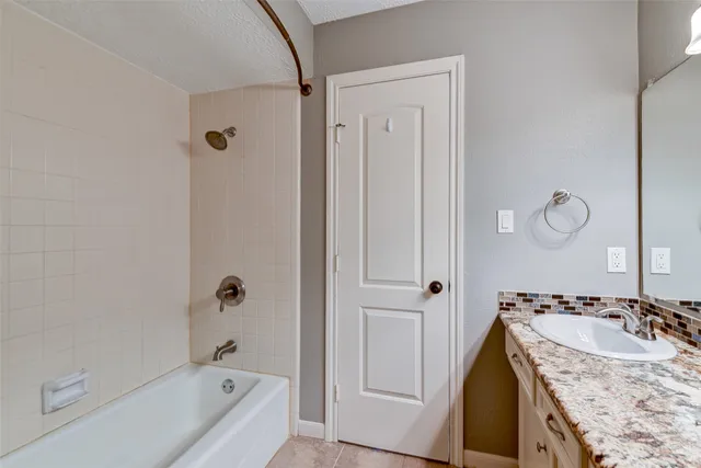 a bathroom with a granite countertop sink a mirror and a bathtub