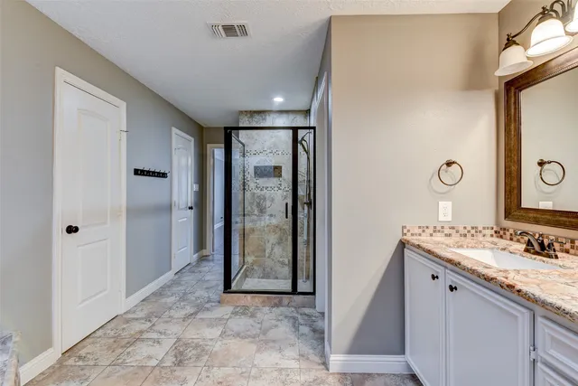 a bathroom with a granite countertop sink a shower and a mirror