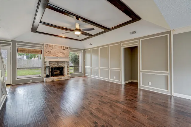 an empty room with wooden floor fireplace and windows