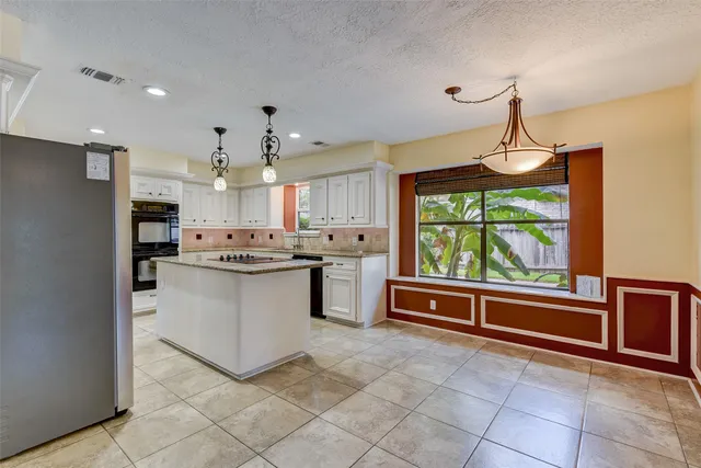 a kitchen with stainless steel appliances granite countertop a refrigerator a sink a stove and white cabinets