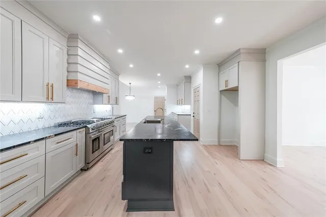 a kitchen with stainless steel appliances granite countertop a sink a stove and a refrigerator