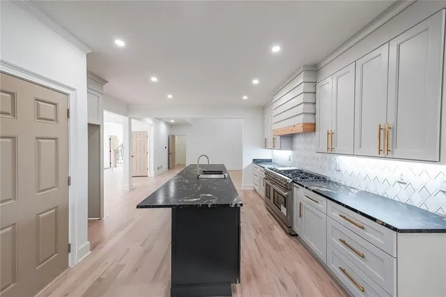 a large kitchen with granite countertop a sink and stainless steel appliances
