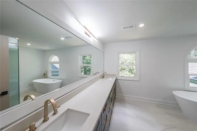 a bathroom with a double vanity sink a large mirror and a bathtub