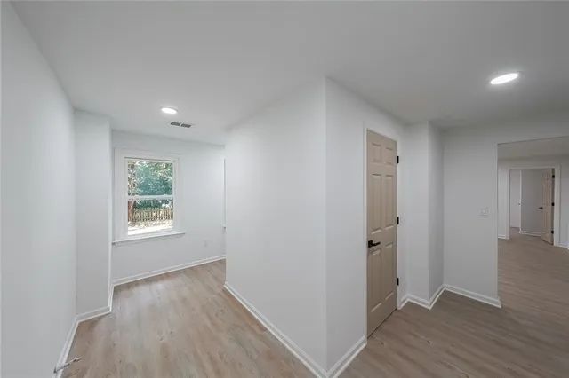 a view of an empty room with window and wooden floor