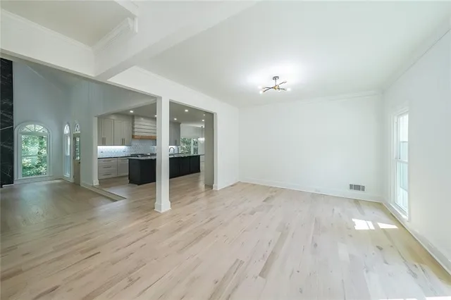 an empty room with wooden floor and kitchen view