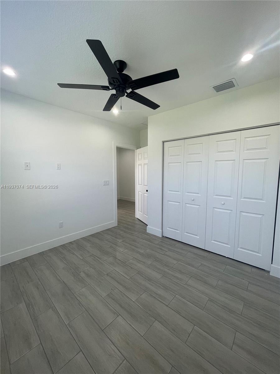 912 West 10th Street Riviera Beach, FL 33404 - Photo 11 of 24 an empty room with wooden floor ceiling fan and windows