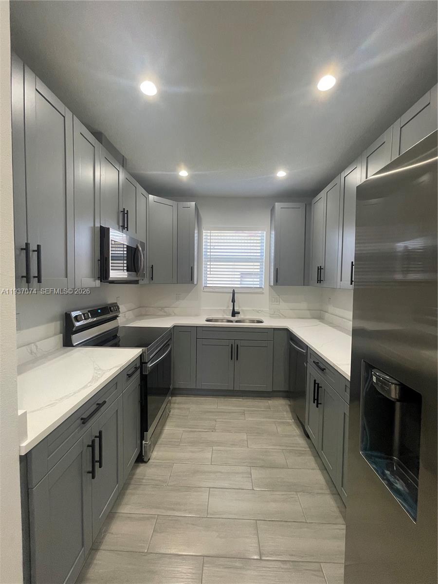 912 West 10th Street Riviera Beach, FL 33404 - Photo 14 of 24 a large kitchen with a large counter top a sink stainless steel appliances and cabinets