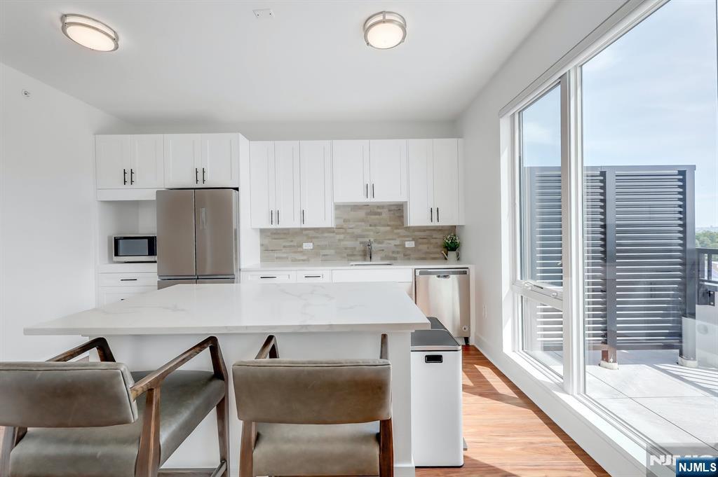 85 Ridge Road, Unit 111 North Arlington, NJ 07031 - Photo 7 of 27 a kitchen with a table chairs refrigerator and cabinets