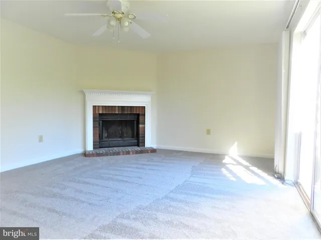 a view of an empty room with a fireplace and a window