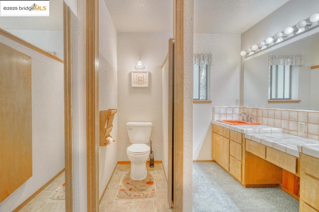 19195 Ferretti Road Groveland, CA 95321 - Photo 13 of 51 Bathroom with light tile patterned floors, double vanity, a textured ceiling, and backsplash, closeted commode.