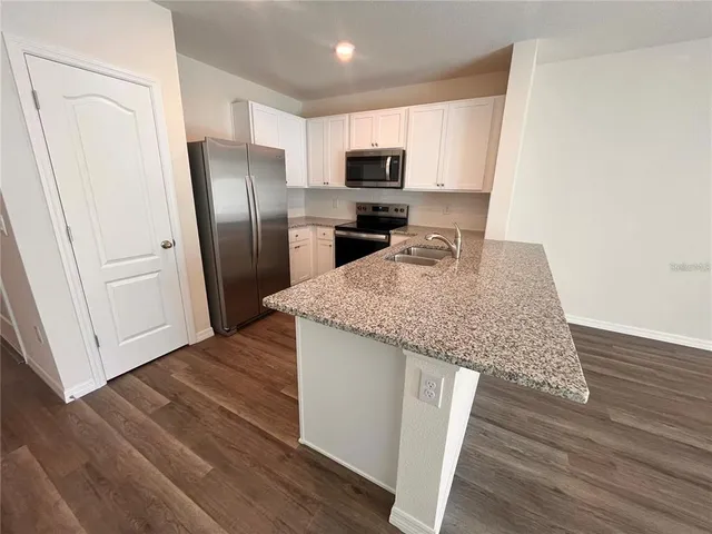a kitchen with granite countertop a refrigerator and microwave