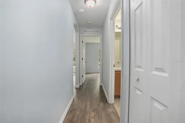 a view of a hallway with wooden floor and a bathroom