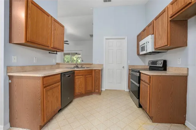 a kitchen with stainless steel appliances granite countertop a stove a sink dishwasher and a refrigerator with wooden cabinets