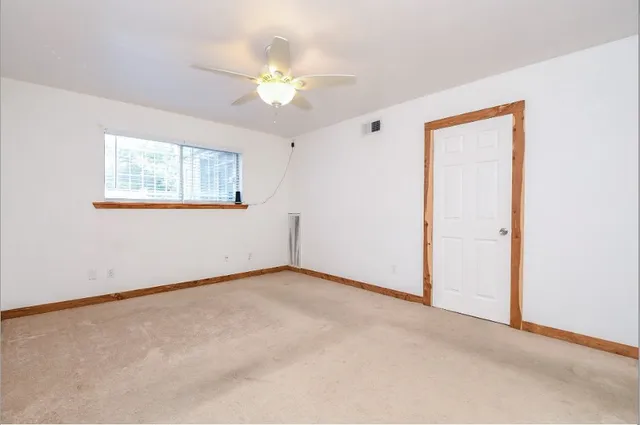 an empty room with windows and chandelier fan
