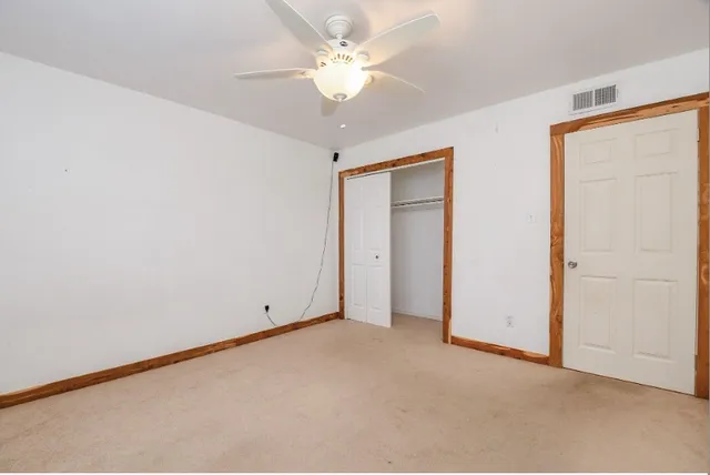 an empty room with a ceiling fan and a window
