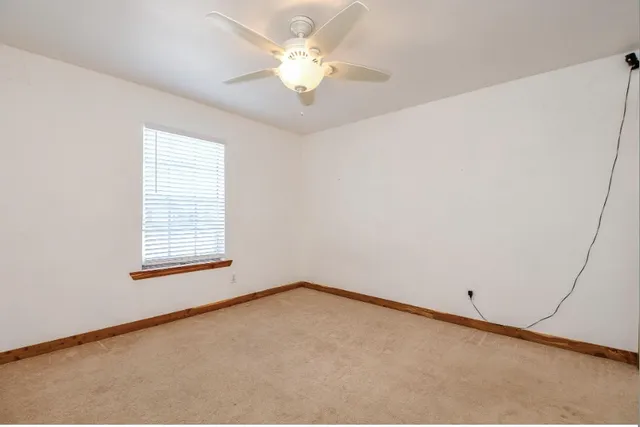 an empty room with a window and a ceiling fan