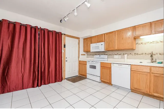 a kitchen with granite countertop a sink window and white stainless steel appliances