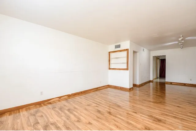 a view of an empty room with wooden floor and a window