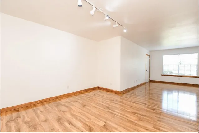 a view of empty room with wooden floor and fan