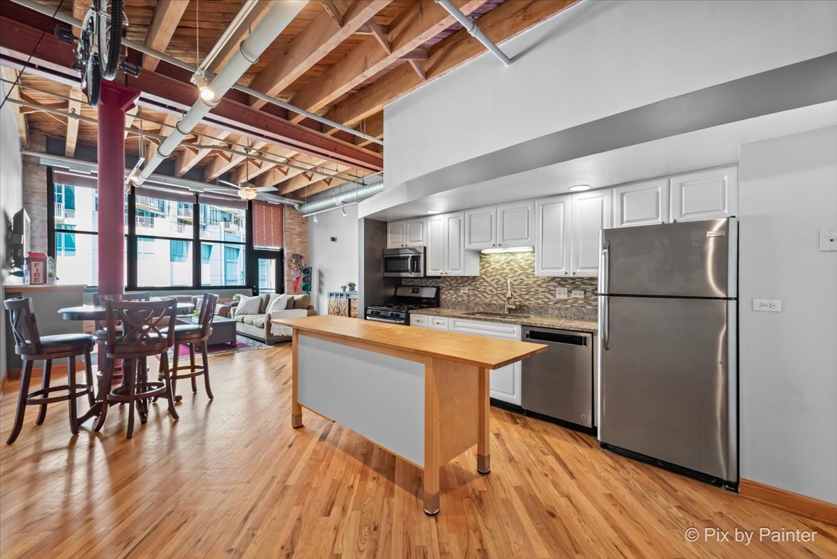 1601 South Indiana Avenue, Unit 306 Chicago, IL 60616 - Photo 4 of 25 a kitchen with stainless steel appliances granite countertop a refrigerator a sink dishwasher a dining table and chairs with wooden floor