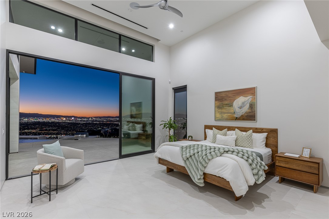 563 Grand Rim Drive Henderson, NV 89012 - Photo 48 of 70 City lights stretch into the horizon from this primary bedroom with high ceilings and vast glass walls.