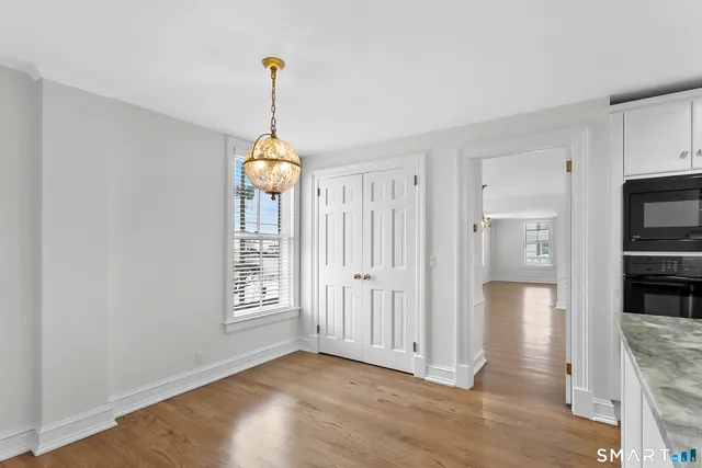 a view of a hallway with wooden floor chandelier and a livingroom