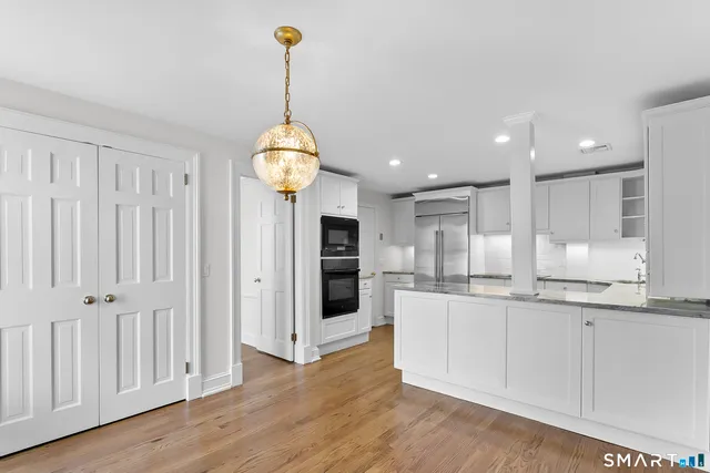 a open kitchen with white cabinets and wooden floor