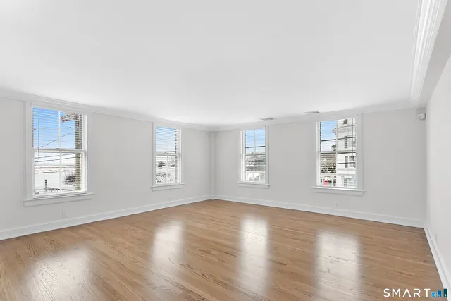 a view of an empty room with wooden floor and window