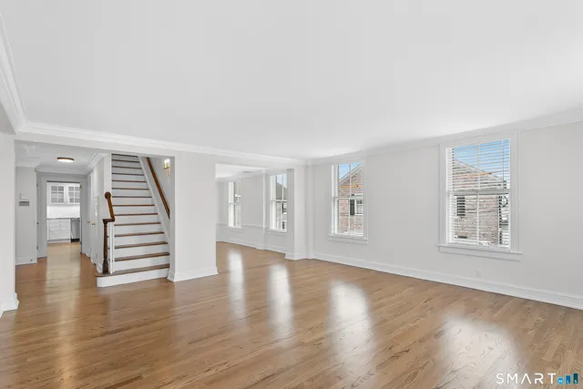 a view of an empty room with wooden floor and window
