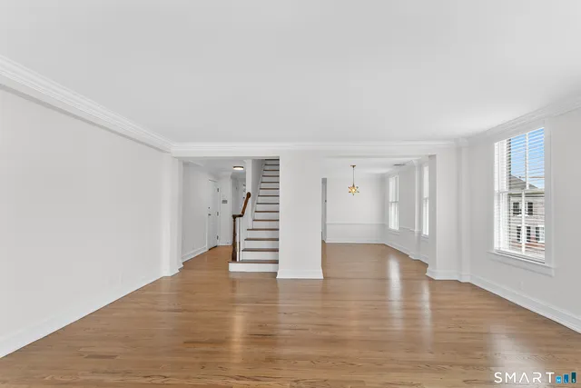 a view of an empty room with wooden floor and stairs