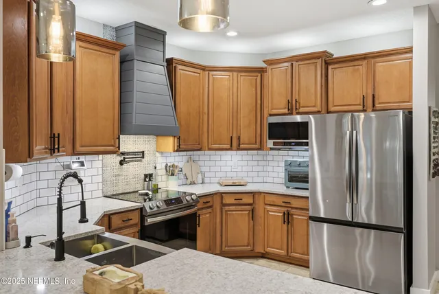 a kitchen with stainless steel appliances granite countertop a refrigerator a sink dishwasher a stove with wooden cabinets and floor