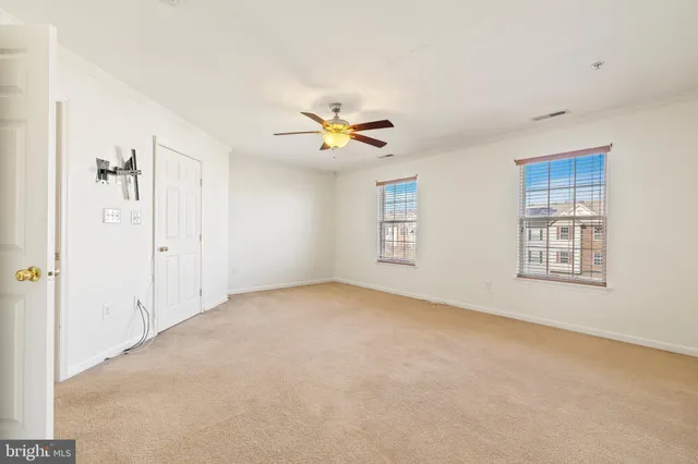 an empty room with windows and fan