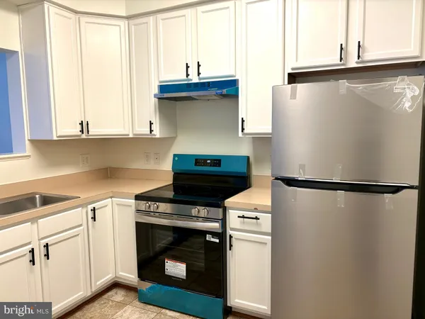 a kitchen with stainless steel appliances white cabinets and a refrigerator