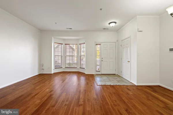 a view of an empty room with wooden floor and window