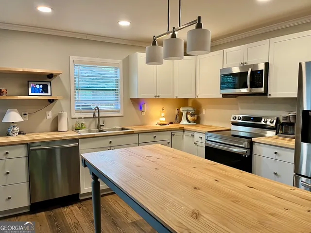 a kitchen with stainless steel appliances a sink dishwasher a stove top oven a refrigerator and cabinets with wooden floor