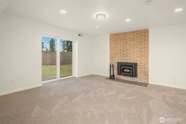 an empty room with kitchen view and fireplace