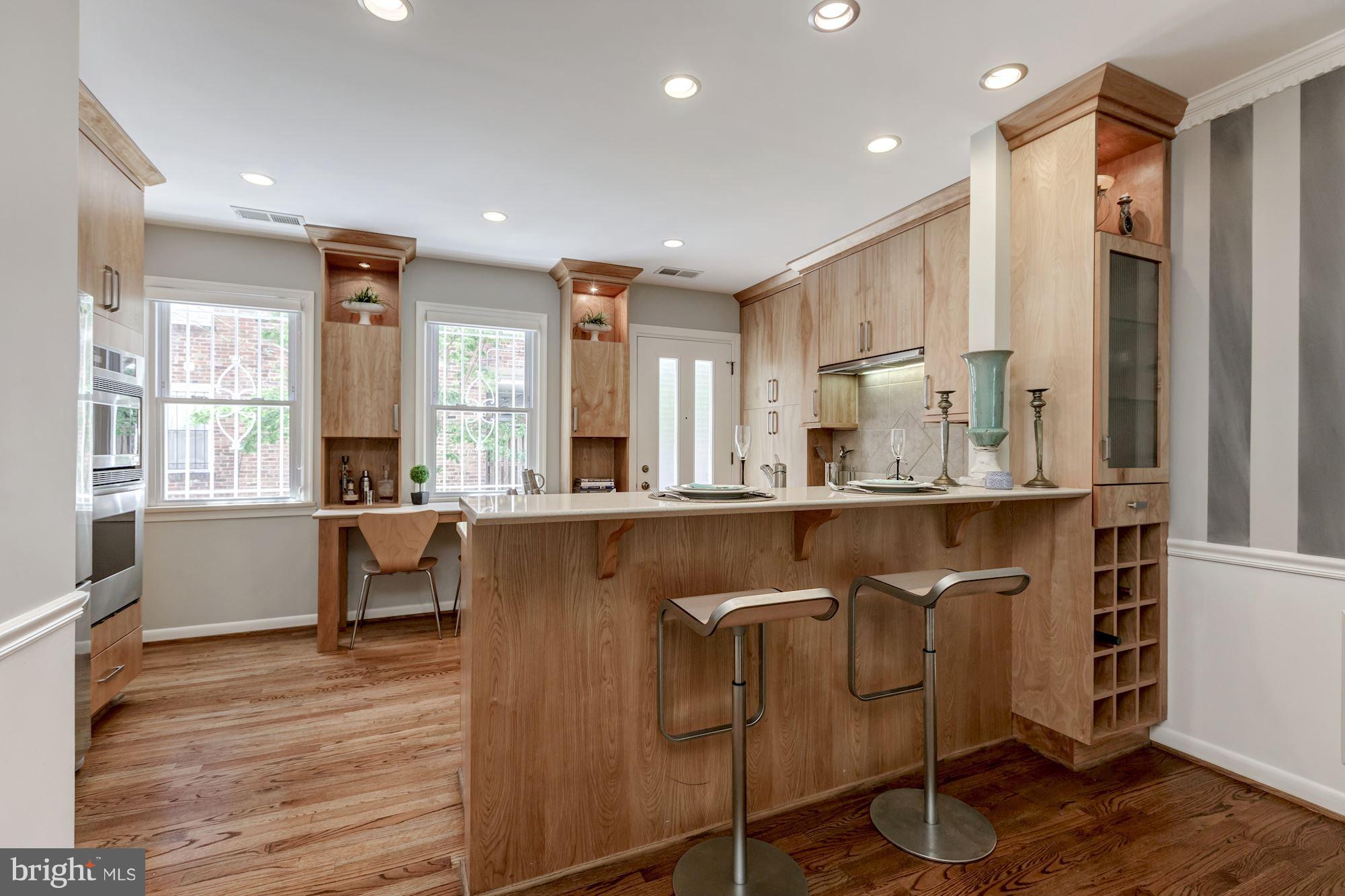 1910 17th Street Northwest Washington, DC 20009 - Photo 8 of 30 a kitchen with kitchen island granite countertop wooden floors and white cabinets