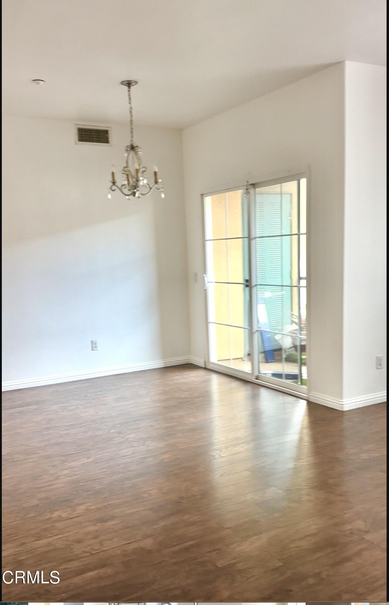 361 Riverpark Boulevard, Unit 303 Oxnard, CA 93036 - Photo 3 of 6 a view of an empty room with wooden floor and a window