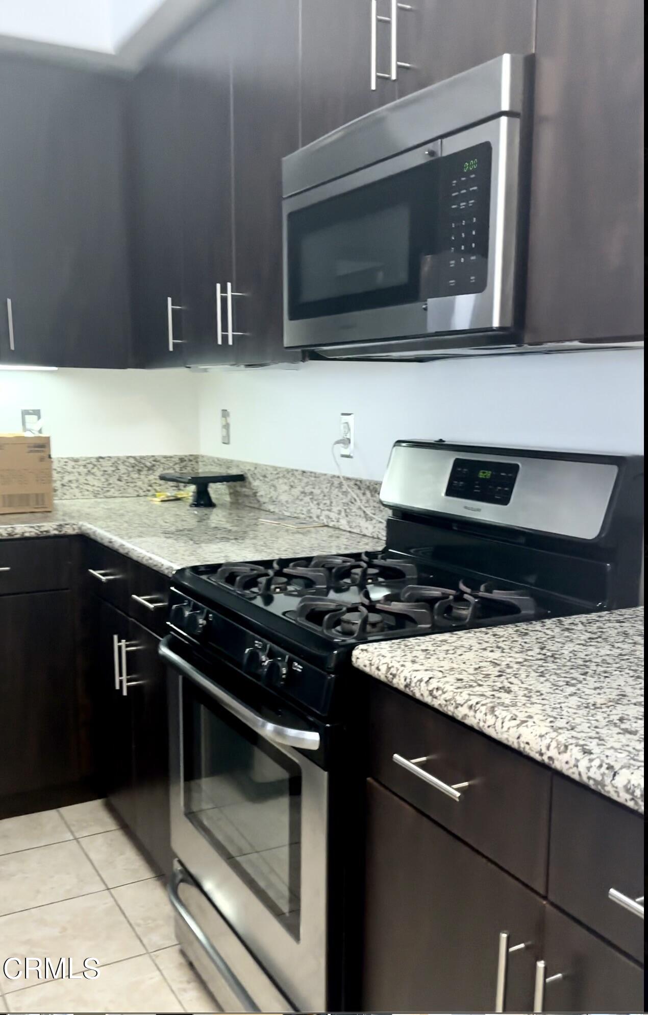 361 Riverpark Boulevard, Unit 303 Oxnard, CA 93036 - Photo 4 of 6 a kitchen with granite countertop stainless steel appliances a stove a microwave and sink