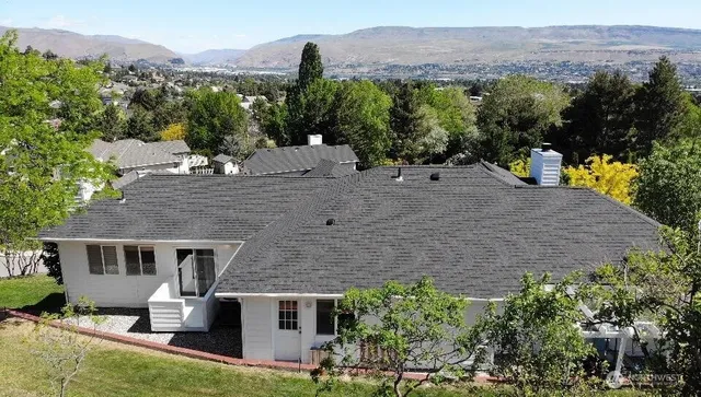 an aerial view of a house with a yard and mountain