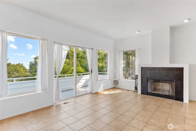 a view of an empty room with windows and a fireplace