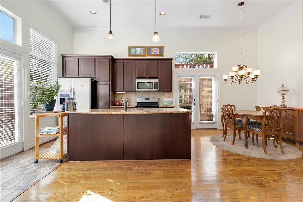4316 Eli Street Houston, TX 77007 - Photo 2 of 20 a kitchen with kitchen island a refrigerator a stove a dining table and chairs with wooden floor