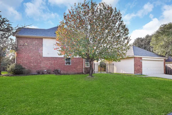 a view of a house with a yard and a large tree