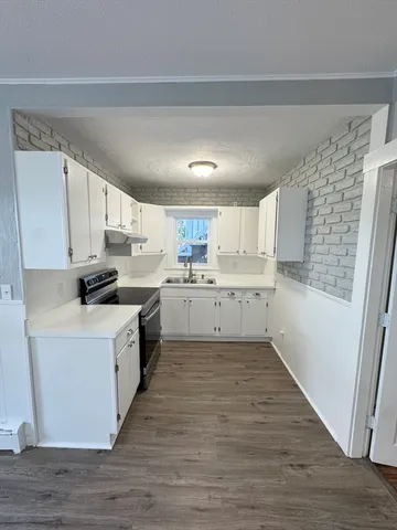 a kitchen with a white cabinets and wooden floor
